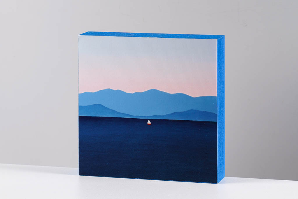 Small artwork of a sailboat and distant island mountains