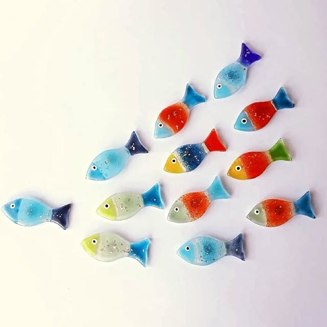 Colourful handmade glass fish displayed on a wall